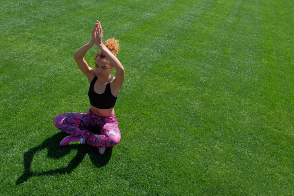 young black girl doing yoga pose on the grass